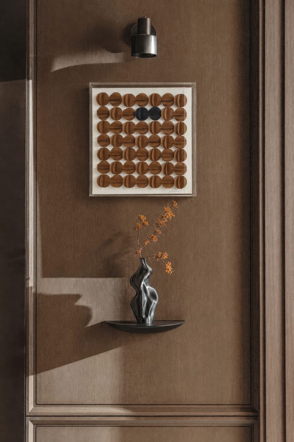 Cuadro de círculos terracota sobre un muro de madera junto a un florero