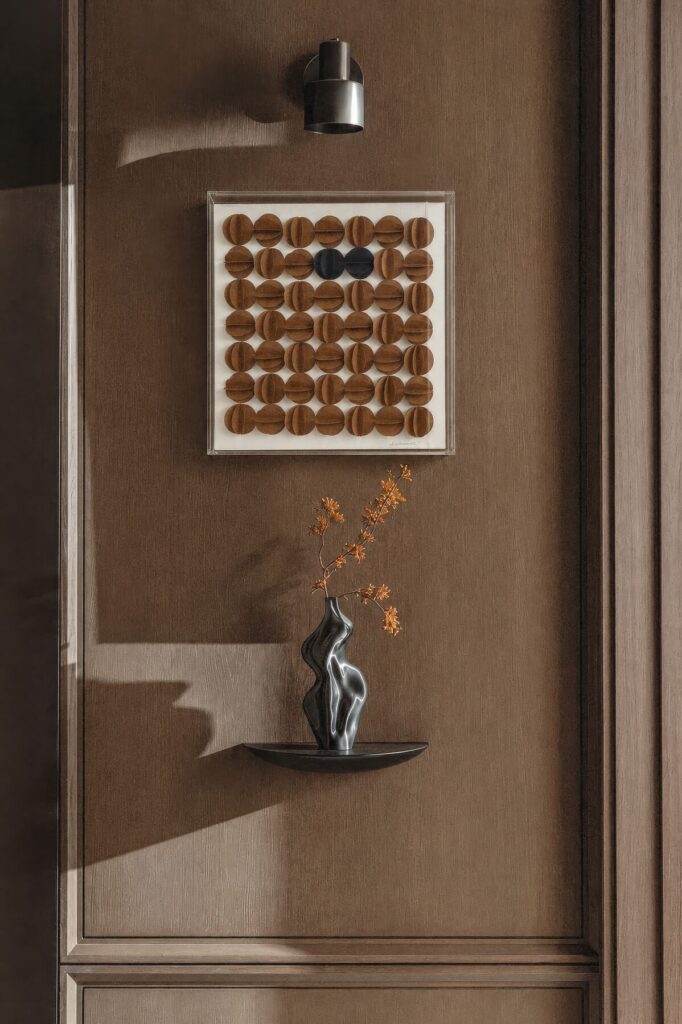 Cuadro de círculos terracota sobre un muro de madera junto a un florero